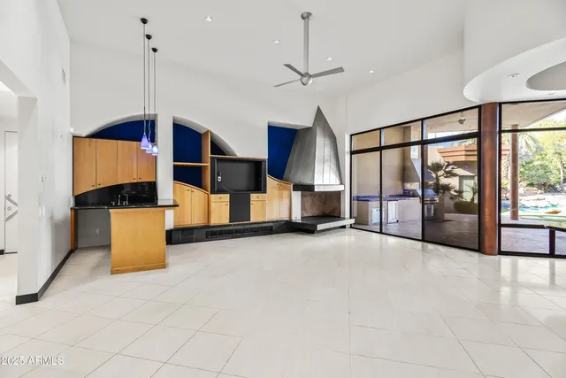 a view of an empty room with kitchen view and a floor to ceiling window