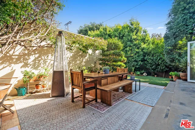 a view of a backyard with lawn chairs potted plants and large tree