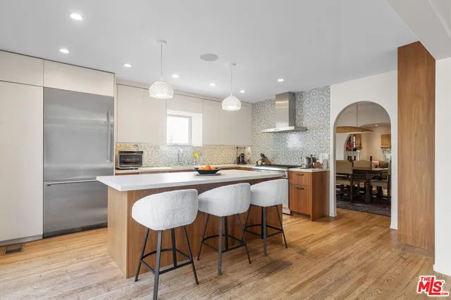 a kitchen with stainless steel appliances granite countertop a sink a stove a refrigerator and wooden floor