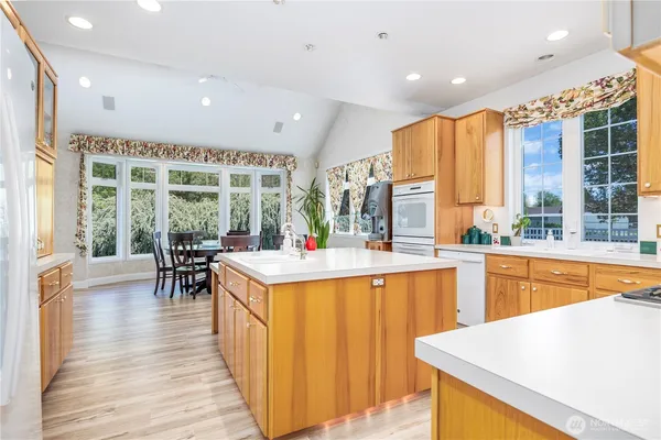a kitchen with stainless steel appliances granite countertop dining table chairs and a large window