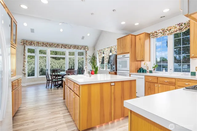a kitchen with stainless steel appliances granite countertop dining table chairs and a large window