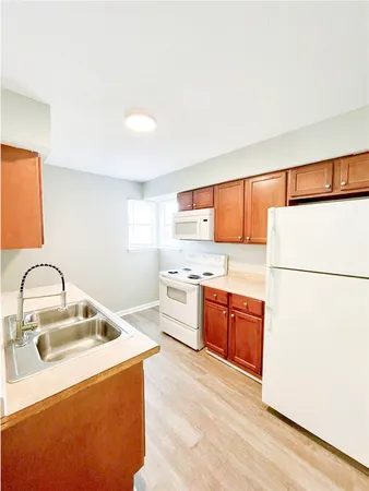 a kitchen with stainless steel appliances granite countertop a sink a stove a refrigerator with white cabinets and wooden floor