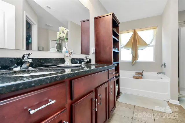 a bathroom with a granite countertop sink mirror and a bathtub