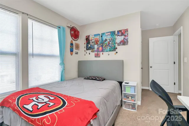 a bedroom with a bed a computer on the desk and a window