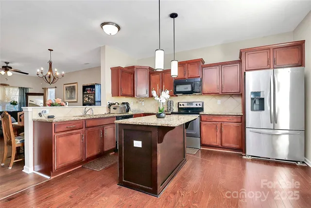 a kitchen with stainless steel appliances granite countertop a refrigerator a sink dishwasher a stove with wooden floor