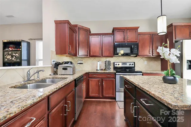 a kitchen with stainless steel appliances granite countertop a sink dishwasher stove and cabinets with wooden floor