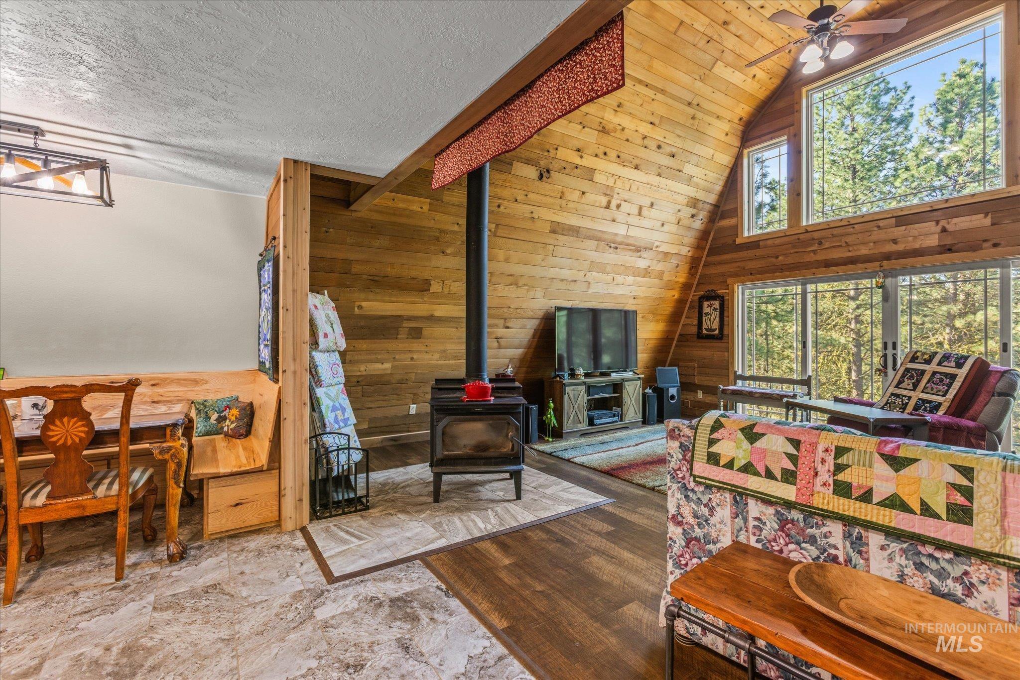 1 Sunset Trail Banks, ID 83602 - Photo 13 of 42 Vaulted wood-paneled ceilings with exposed beams, wood-finish flooring, a built-in wood-burning stove, and expansive windows offering natural light