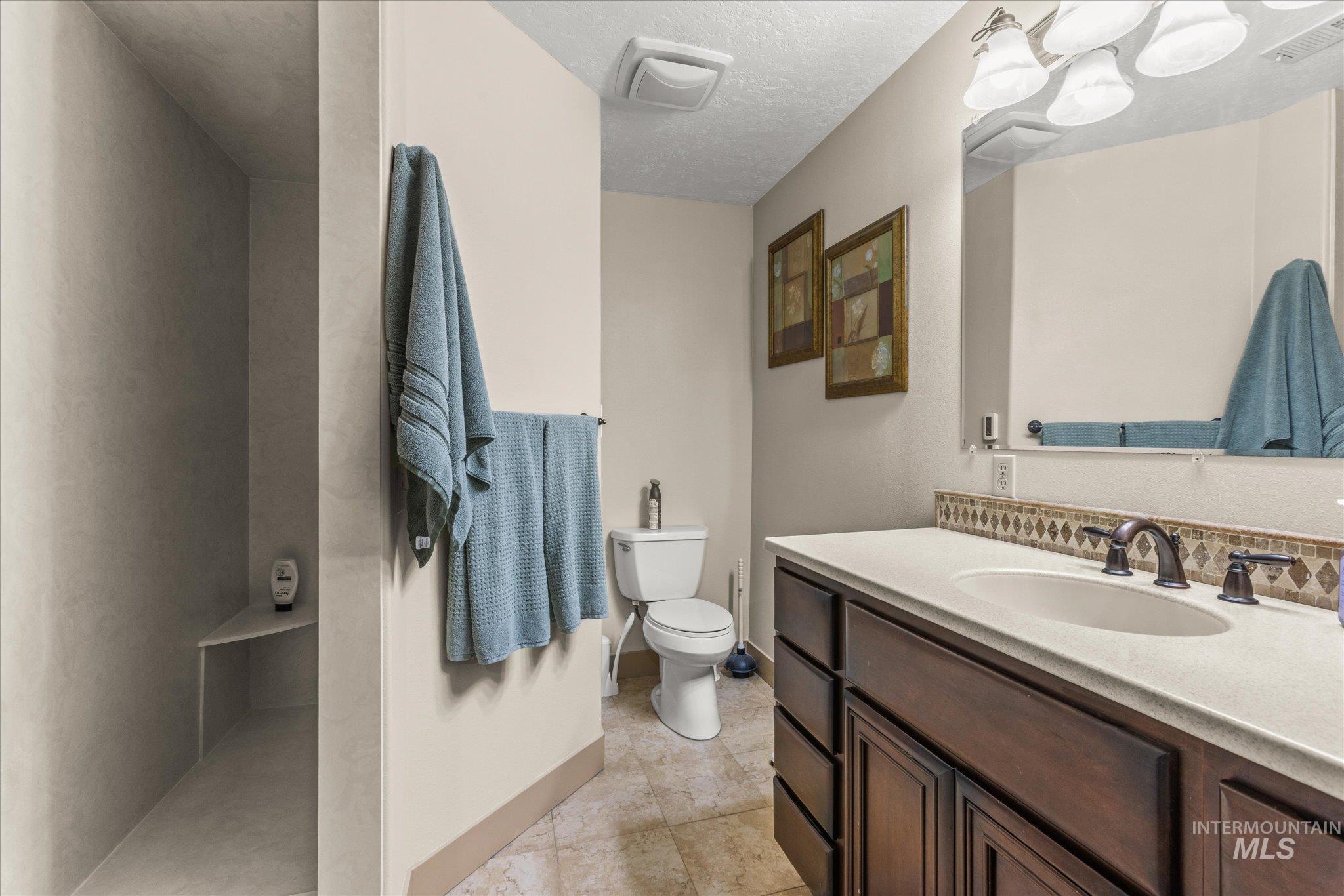 1 Sunset Trail Banks, ID 83602 - Photo 21 of 42 Full bathroom featuring a dark wood-finish vanity with an integrated sink and light-colored countertop, complemented by a decorative tile backsplash