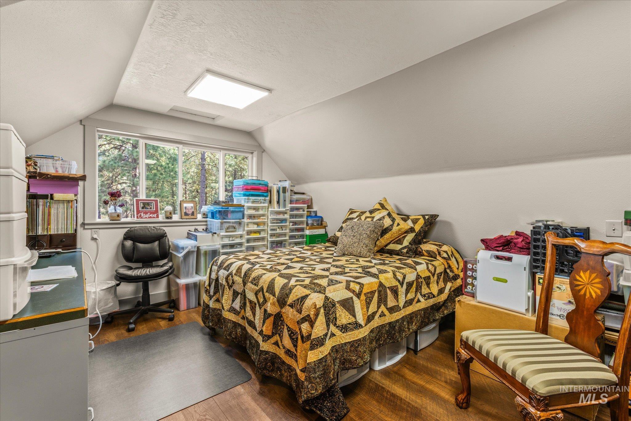 1 Sunset Trail Banks, ID 83602 - Photo 24 of 42 Attic room featuring a wide window with exterior tree scenery, wood-finish flooring, a sloped ceiling, and a flush-mount rectangular light fixture