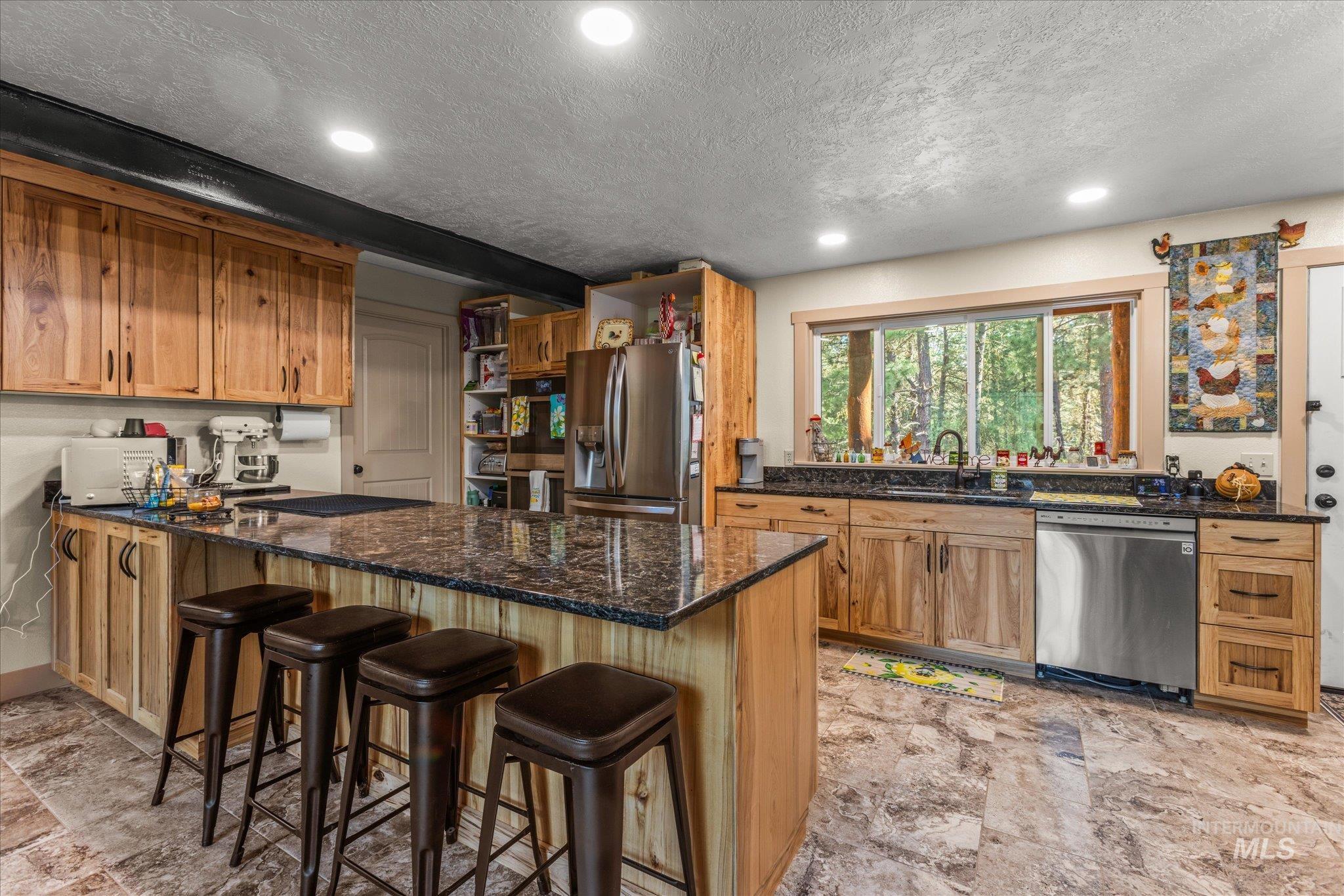 1 Sunset Trail Banks, ID 83602 - Photo 3 of 42 Kitchen featuring an island with stone countertop, wood cabinetry, recessed lighting, stainless steel appliances, and tile flooring