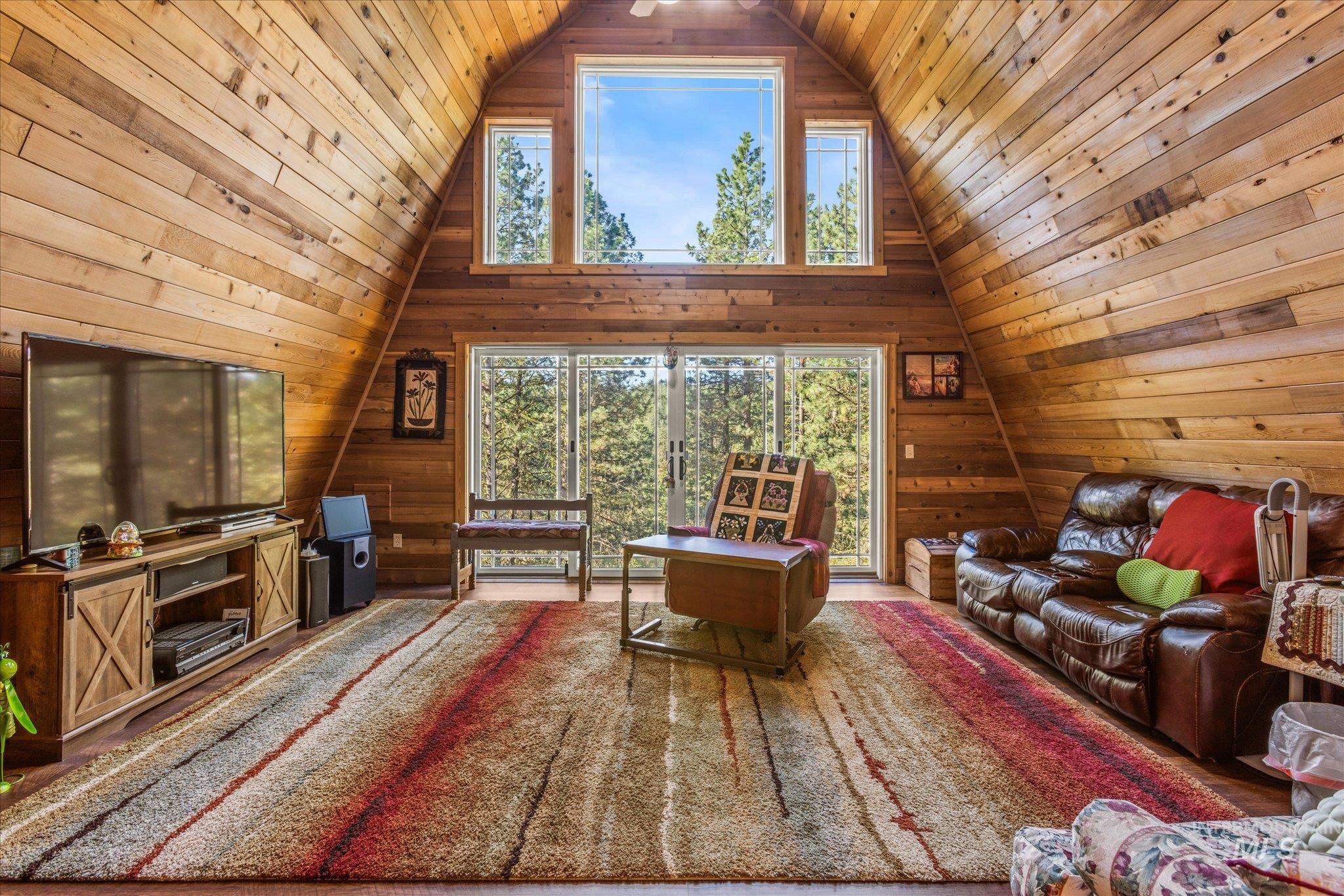 1 Sunset Trail Banks, ID 83602 - Photo 8 of 42 Open-concept living space featuring wood-paneled walls and ceiling, a vaulted ceiling with a fan, and large picture windows