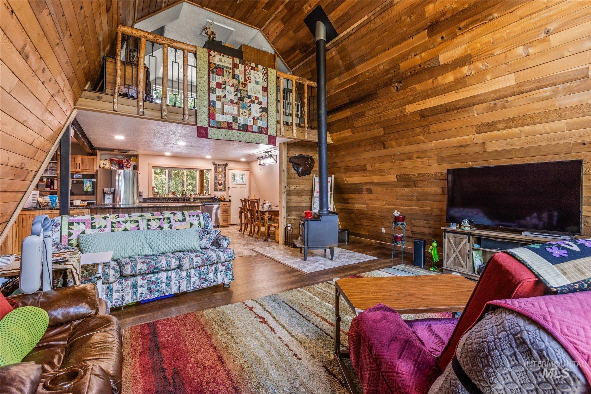 1 Sunset Trail Banks, ID 83602 - Photo 9 of 42 Vaulted wood-paneled ceilings with exposed beams, wood-finish flooring, a built-in wood-burning stove, and an open-concept kitchen with wood cabinetry