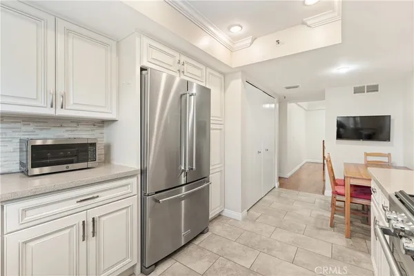 a view of kitchen with stainless steel appliances wooden floor and living room view