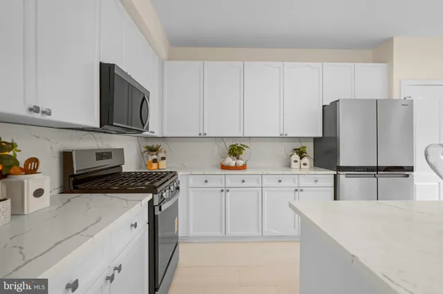 a kitchen with stainless steel appliances white cabinets and a refrigerator