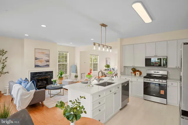 a kitchen with stainless steel appliances a stove a sink a oven a counter space and living room view