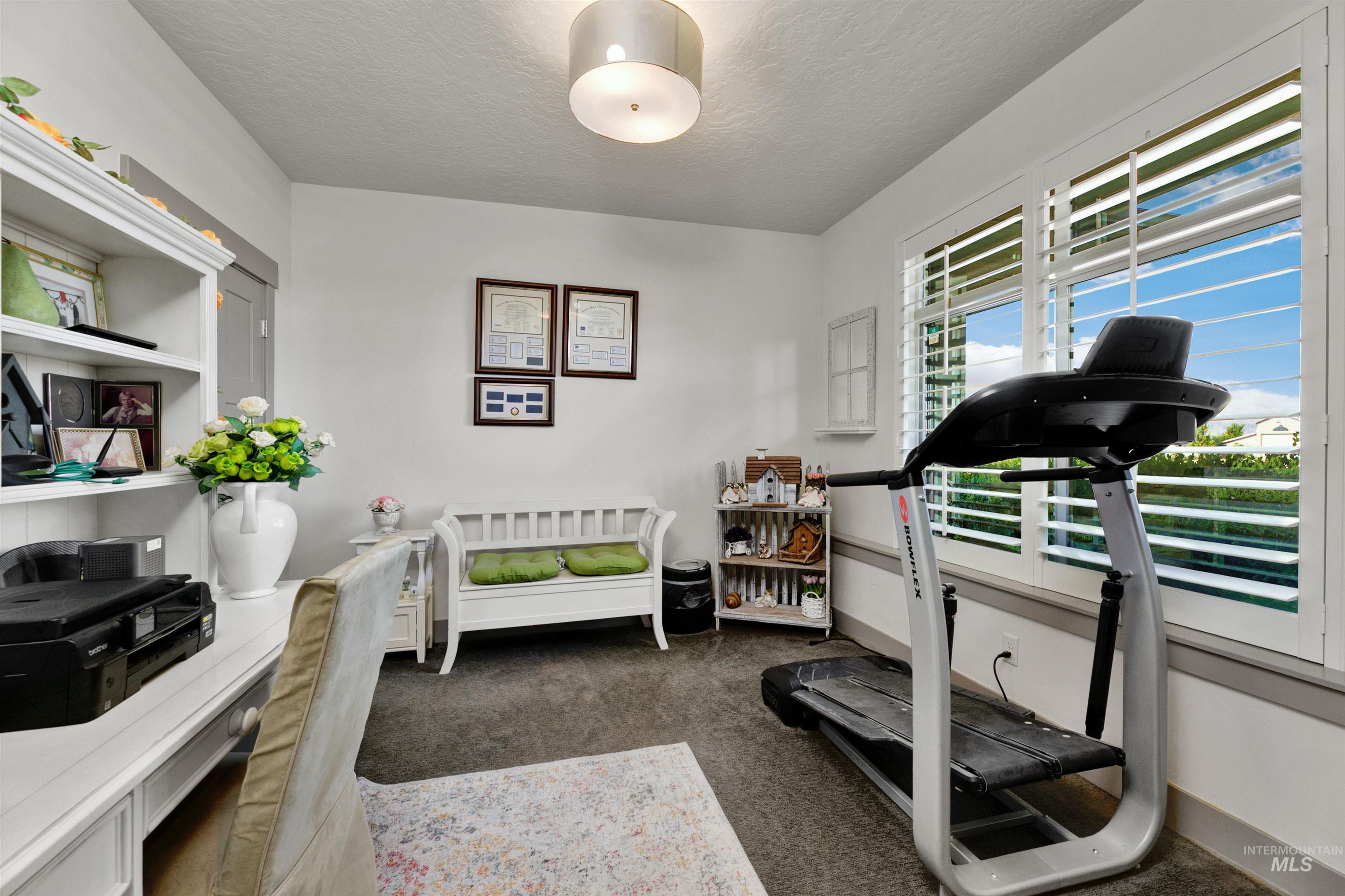 24398 Tombstone Ridge Court Middleton, ID 83644 - Photo 7 of 47 Bright room with plantation shutters, a white built-in desk with shelving, and a modern overhead light fixture