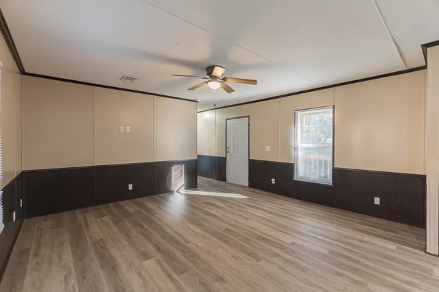 a view of an empty room with a window and wooden floor