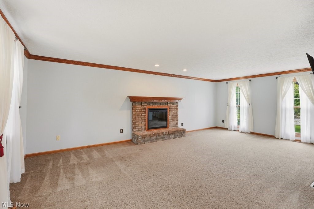 5321 Young Road Stow, OH 44224 - Photo 10 of 37 Spacious room featuring a brick fireplace with a wood mantle, recessed lighting, crown molding, and multiple windows