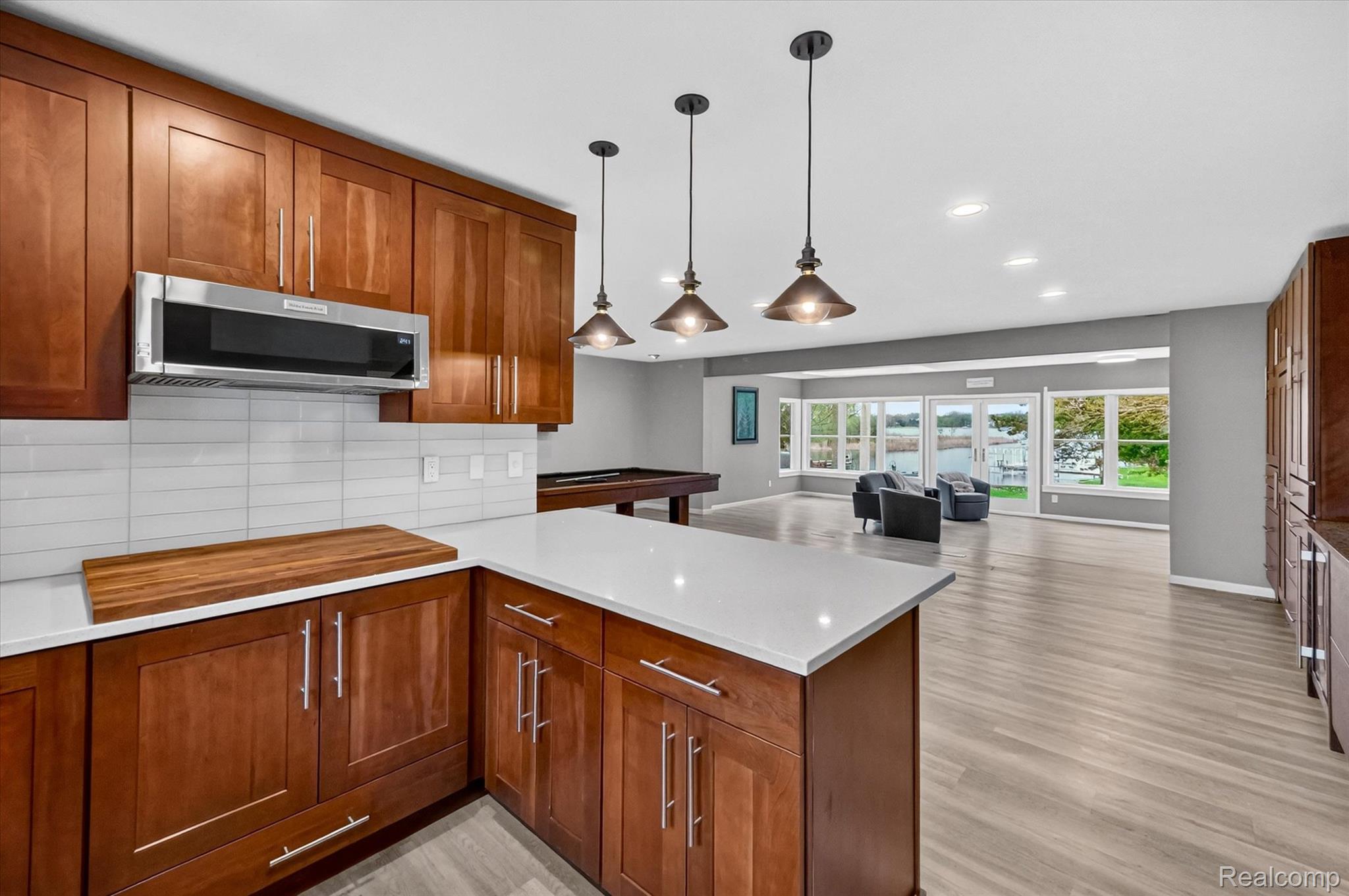 2264 Crane Road Fenton, MI 48430 - Photo 54 of 55 Kitchen featuring open floor plan, wood finish cabinetry, pendant lighting, backsplash, and stainless steel microwave