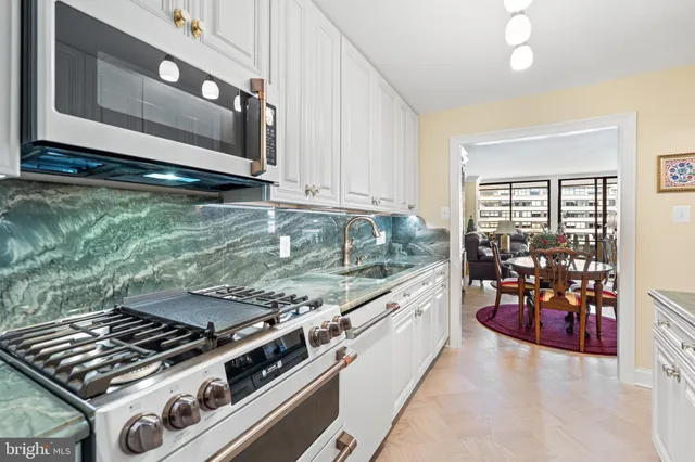 a kitchen with granite countertop white cabinets and stainless steel appliances