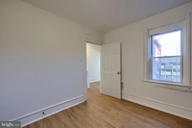 an empty room with wooden floor and fan
