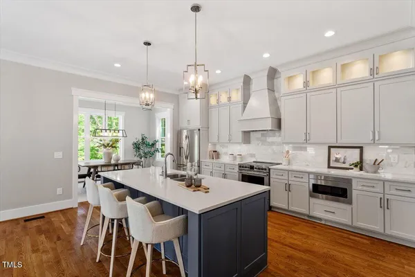 a kitchen with stainless steel appliances kitchen island granite countertop a kitchen island hardwood floor and a sink