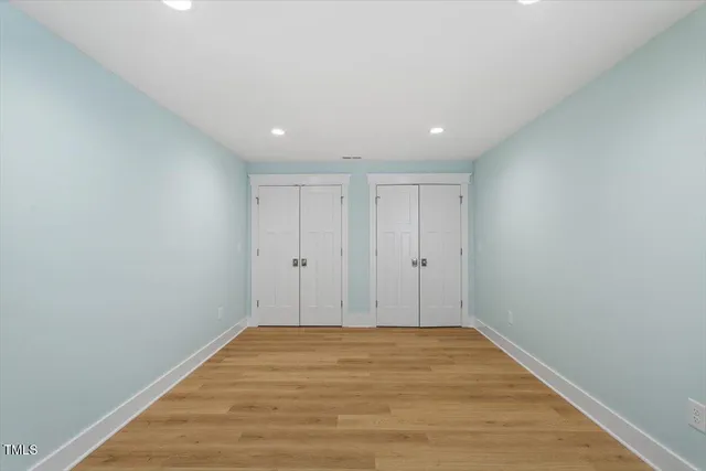 an empty room with wooden floor and a ceiling fan