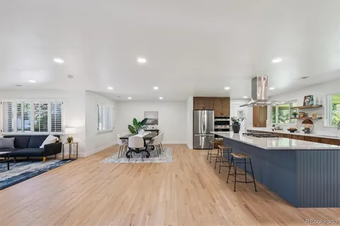 a living room with stainless steel appliances granite countertop furniture wooden floor and a view of kitchen