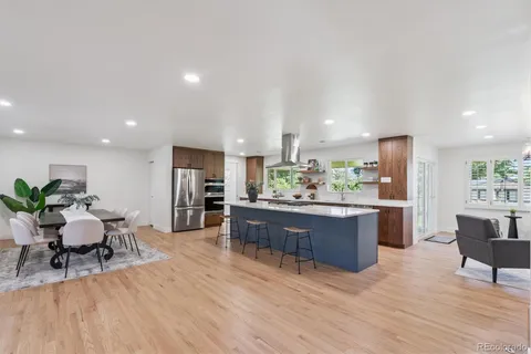 a room with stainless steel appliances kitchen island granite countertop furniture wooden floor and a view of kitchen