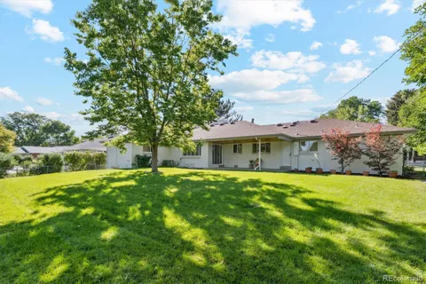 a view of a house with a big yard plants and large trees
