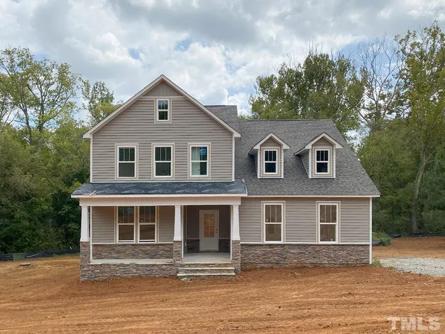 a front view of a house with yard and trees