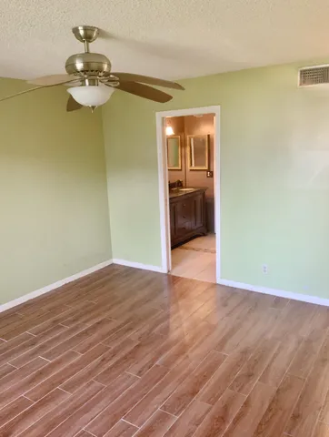 a view of a room with wooden floor a ceiling fan and a bathroom