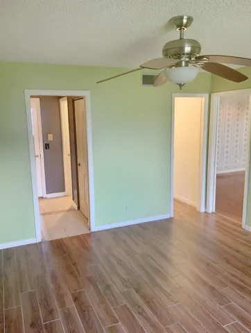 an empty room with wooden floor fan and windows