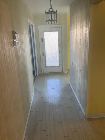 a view of hallway with window and wooden floor