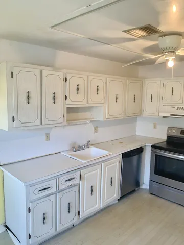 a kitchen with white cabinets white stainless steel appliances and sink