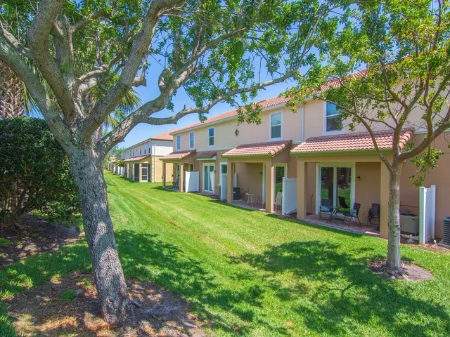 a view of a white house with a big yard and large tree