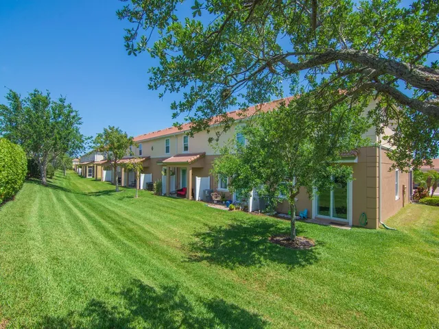 a view of a house next to a big yard and large trees