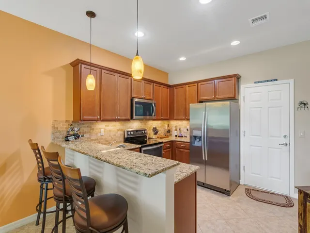 a kitchen with a refrigerator a sink and chairs