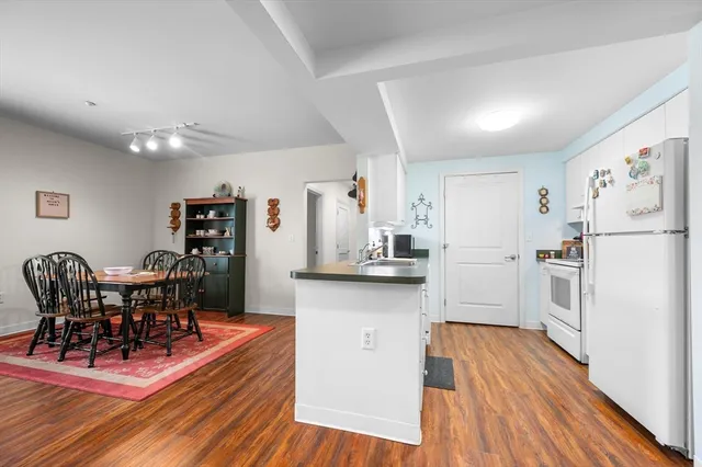 a kitchen with stainless steel appliances a refrigerator a stove a dining table and chairs with wooden floor