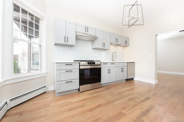 a kitchen with stainless steel appliances white cabinets and wooden floor
