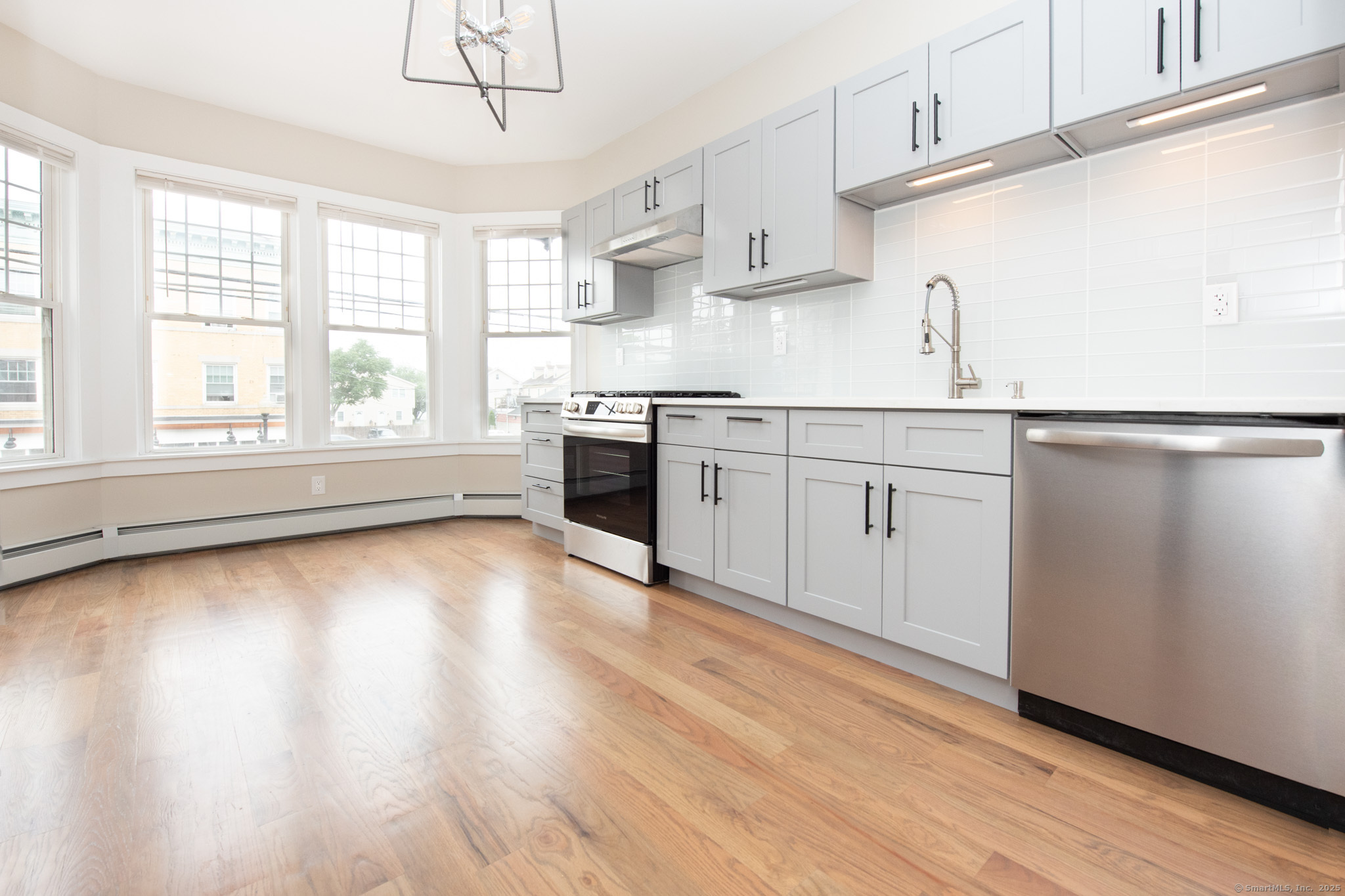 527 East Main Street Bridgeport, CT 06608 - Photo 4 of 25 a kitchen with stainless steel appliances granite countertop a stove a sink and white cabinets with wooden floor