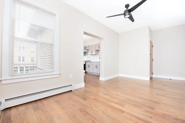 a view of an empty room with a window and wooden floor