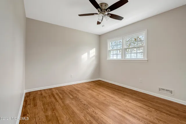 a view of a big room with wooden floor and windows