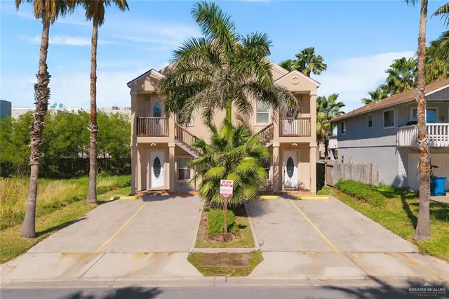 a front view of a house with a yard and potted plants