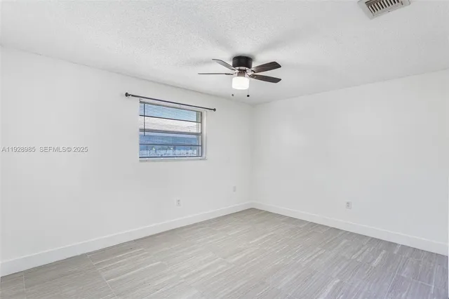 an empty room with wooden floor closet and fan