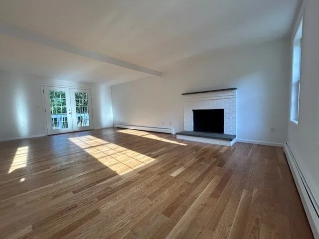 wooden floor fireplace and windows in an empty room