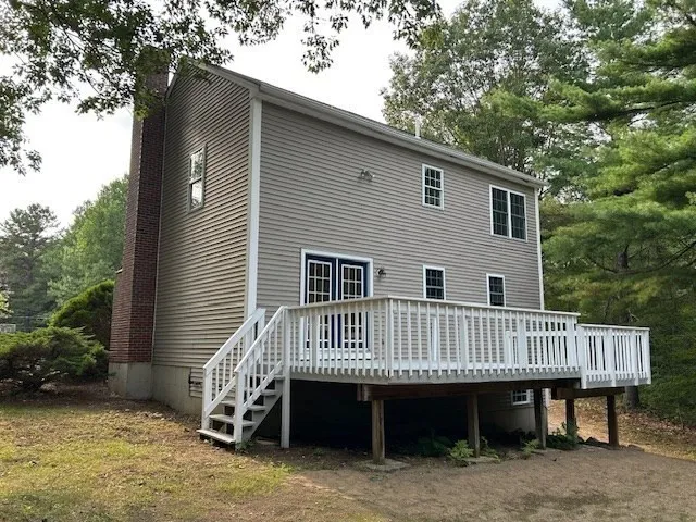 a view of a house with a yard and deck area under a large tree
