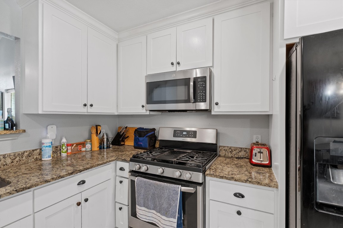 2601 Turtle River Drive Leander, TX 78641 - Photo 8 of 32 a kitchen with granite countertop white cabinets and stainless steel appliances