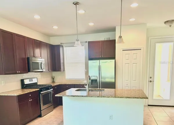 a kitchen with kitchen island granite countertop a sink a counter top space appliances and cabinets