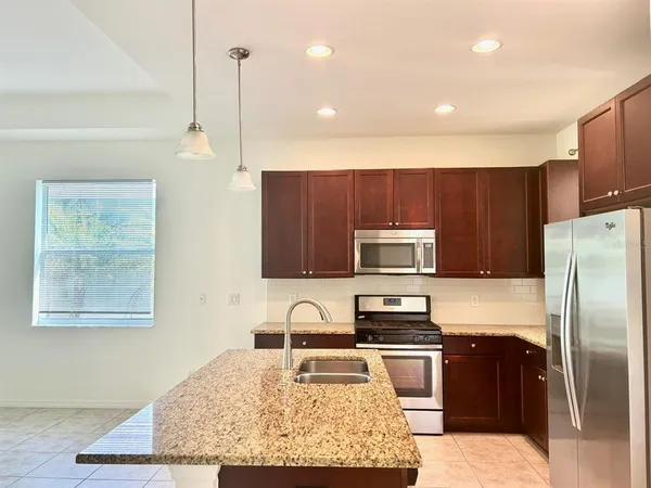 a kitchen with kitchen island granite countertop stainless steel appliances and wooden cabinets